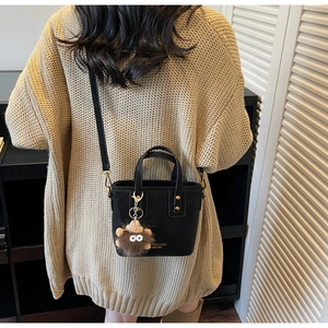 Détail d'un sac seau noir avec marquage doré et charm en peluche monstre rigolo