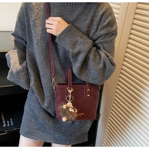 Détail d'un mini sac cabas bordeaux avec breloque monstre et bandoulière réglable