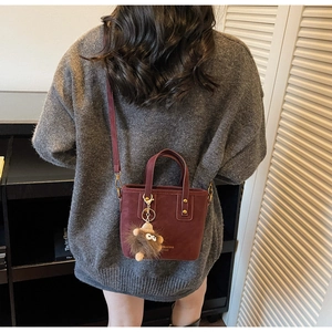 Détail du sac cabas en cuir bordeaux avec porte-clés monstre en peluche et bandoulière