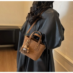 Close-up of brown matte PU leather crossbody bag featuring a cute monster charm accessory