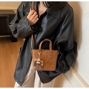 Détail du sac seau marron mat avec rivets dorés et breloque peluche amusante