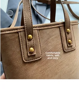 Close-up of brown textured leather handbag with gold rivet details and reinforced stitching