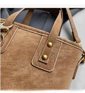 Macro shot of gold-tone hardware and litchi texture on a brown leather bucket bag