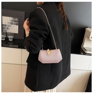 Detailed view of pink glitter evening bag featuring a gold leaf clasp and metal chain