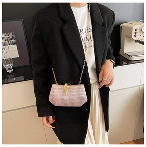 Detail of pink glitter evening bag featuring a gold leaf clasp and chain shoulder strap
