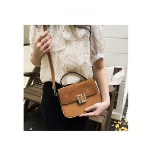 Detail of a brown leather saddle bag with matte suede patchwork and silver buckle