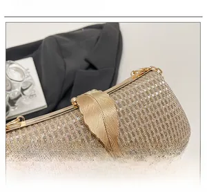 Macro detail of golden metal leaf clasp and metallic woven fabric on evening clutch bag