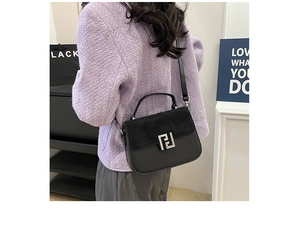Side view of luxury black matte patchwork leather saddle bag worn with a tweed jacket