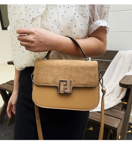 Detail of color-block saddle bag featuring textured suede flap and metallic F-shaped buckle