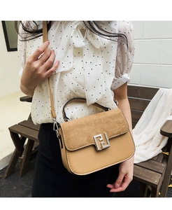 Detail of a two-tone saddle bag with suede flap and geometric square metal buckle