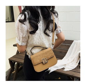 Macro detail of brown leather saddle bag with silver F-shaped buckle and frosted texture