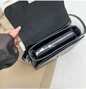 Detail view of the black matte leather crossbody bag showing inner compartments and zipper
