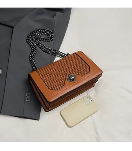 Detailed view of the woven V-pattern texture and metal lock on the brown chain bag