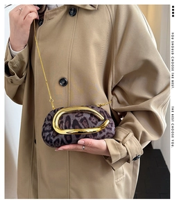 Detail of leopard print faux suede crossbody bag with gold U-shaped metal handle and chain