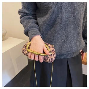 Detail of leopard print suede handbag featuring a bold gold ring handle and metal chain