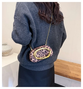 Detail of leopard print suede crossbody bag featuring a large C-shaped gold metal buckle