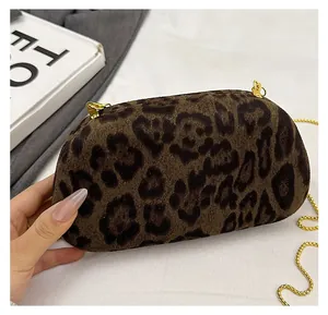 Close-up of leopard print suede texture and elegant gold metal chain on clutch bag