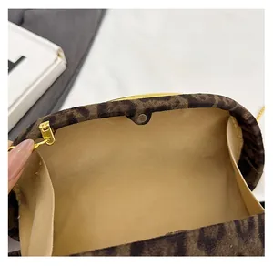 Detail of leopard print suede clutch with magnetic clasp and gold chain attachments