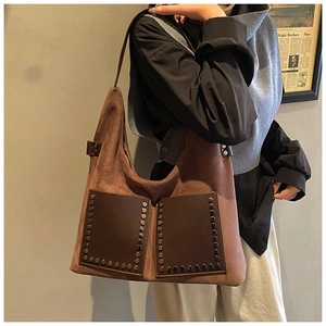 Macro view of vintage brown suede tote bag featuring metallic stud rivets and pockets
