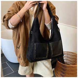 Detail of vintage black suede hobo bag featuring silver rivets and square front pockets