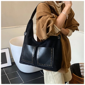 Detail of vintage black suede hobo bag with metal rivets and large pockets on front