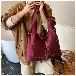 Detail of dark burgundy suede tote bag with silver rivet studs on a model's shoulder