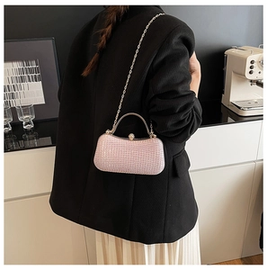 Detailaufnahme einer fliederfarbenen Perlen-Abendtasche mit goldener Kette am Blazer