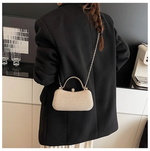 Detail der champagner gold Glitzer-Abendtasche mit Kette, getragen von einem Model im Anzug
