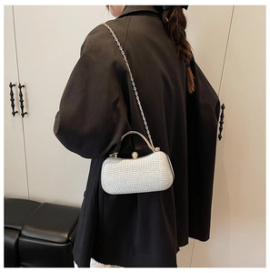 Detailansicht einer silbernen Perlen-Abendtasche mit Metallgriff auf schwarzem Mantel