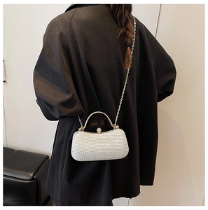 Detailansicht der silbernen Glitzer-Clutch mit Kristallschloss und Metallgriff am Model