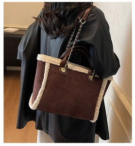 Detail of suede tote bag with faux shearling trim and golden chain on shoulder