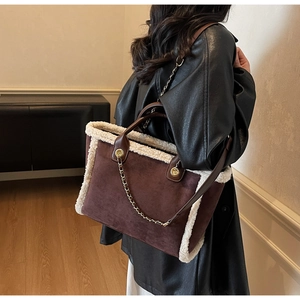 Detail of faux shearling trim on a brown suede tote bag with metal chain strap