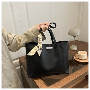 Detail of black tote bag featuring a decorative silk scarf and silver metal buckle