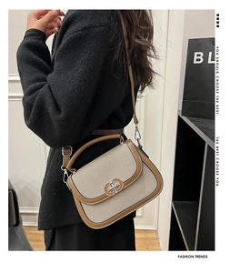 Detail of canvas saddle bag with brown leather trim and silver metal buckle on a model