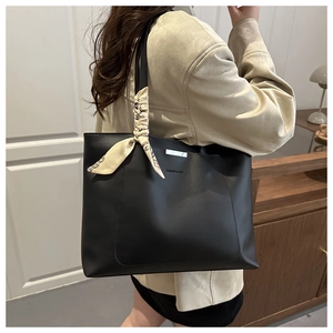 Detail of black matte PU tote bag with metal bar and vintage scarf on the handle