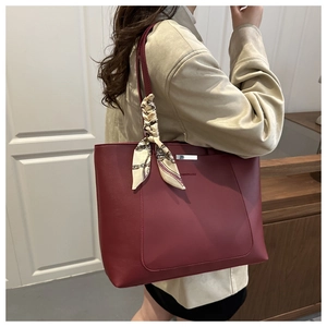 Detail of burgundy tote bag with silver metal bar and silk scarf handle decoration
