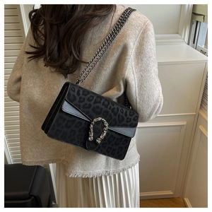 Detail of leopard print chain bag featuring a silver horseshoe tiger head buckle on a model