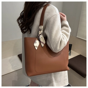 Close-up of caramel tote bag with silk scarf detail worn with a cream wool coat