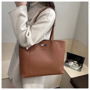 Brown leather tote bag for women showing large capacity and fashion metal bar detail