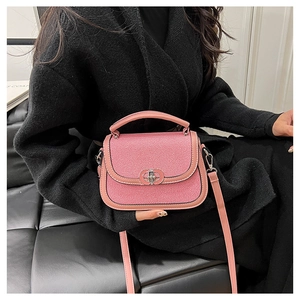Detail of pink saddle bag with textured fabric flap and silver interlocking metal clasp