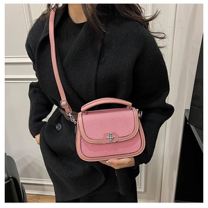 Detail of pink saddle bag with textured fabric, leather trim, and silver metal twist lock