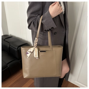 Detail of khaki tote bag with floral silk scarf handle and black metal trim on pocket