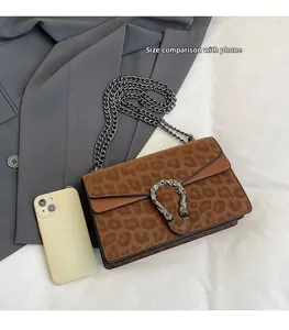Detail view of leopard print crossbody bag with tiger head buckle and phone for scale