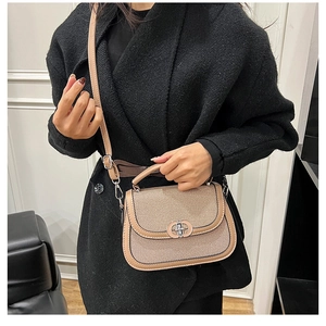 Detail of khaki textured saddle bag with leather trim and silver metal twist lock