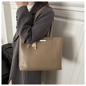 Detail of khaki tote bag featuring silk scarf handle and silver metal trim on grey suit