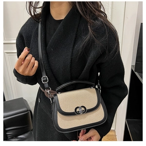 Model wearing a beige woven saddle bag with black leather trim and silver metal buckle