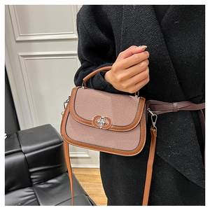 Detail of a brown leather saddle bag with beige woven panel and metallic turn-lock