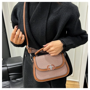 Close-up of brown patchwork saddle bag featuring vintage metal lock and striped texture
