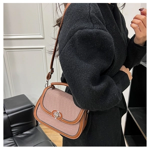 Detail of woven texture and brown leather trim on a stylish saddle bag with metal clasp