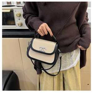 Détail d'un sac selle rétro en cuir noir et paille tressée avec logo métallique